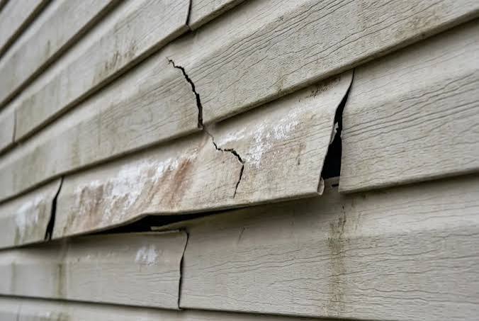 Cracked and split lap siding on the side of a house