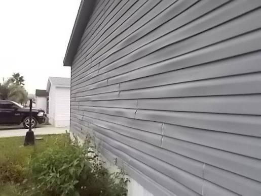 Warped and wavy vinyl siding buckling along the wall